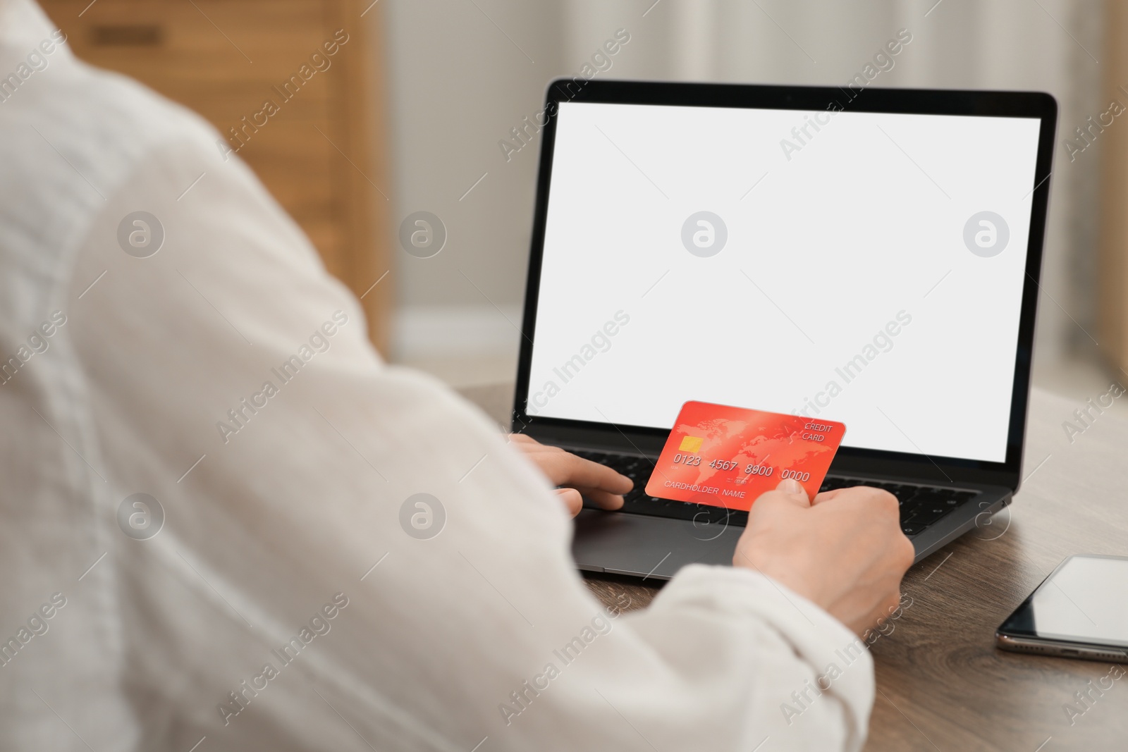 Photo of Woman with credit card using laptop for online shopping at wooden table indoors, closeup