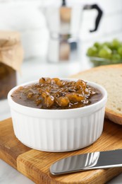 Photo of Delicious gooseberry jam and knife on white table, closeup