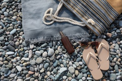 Photo of Stylish bag, flip flops and spray on stones outdoors, flat lay. Space for text