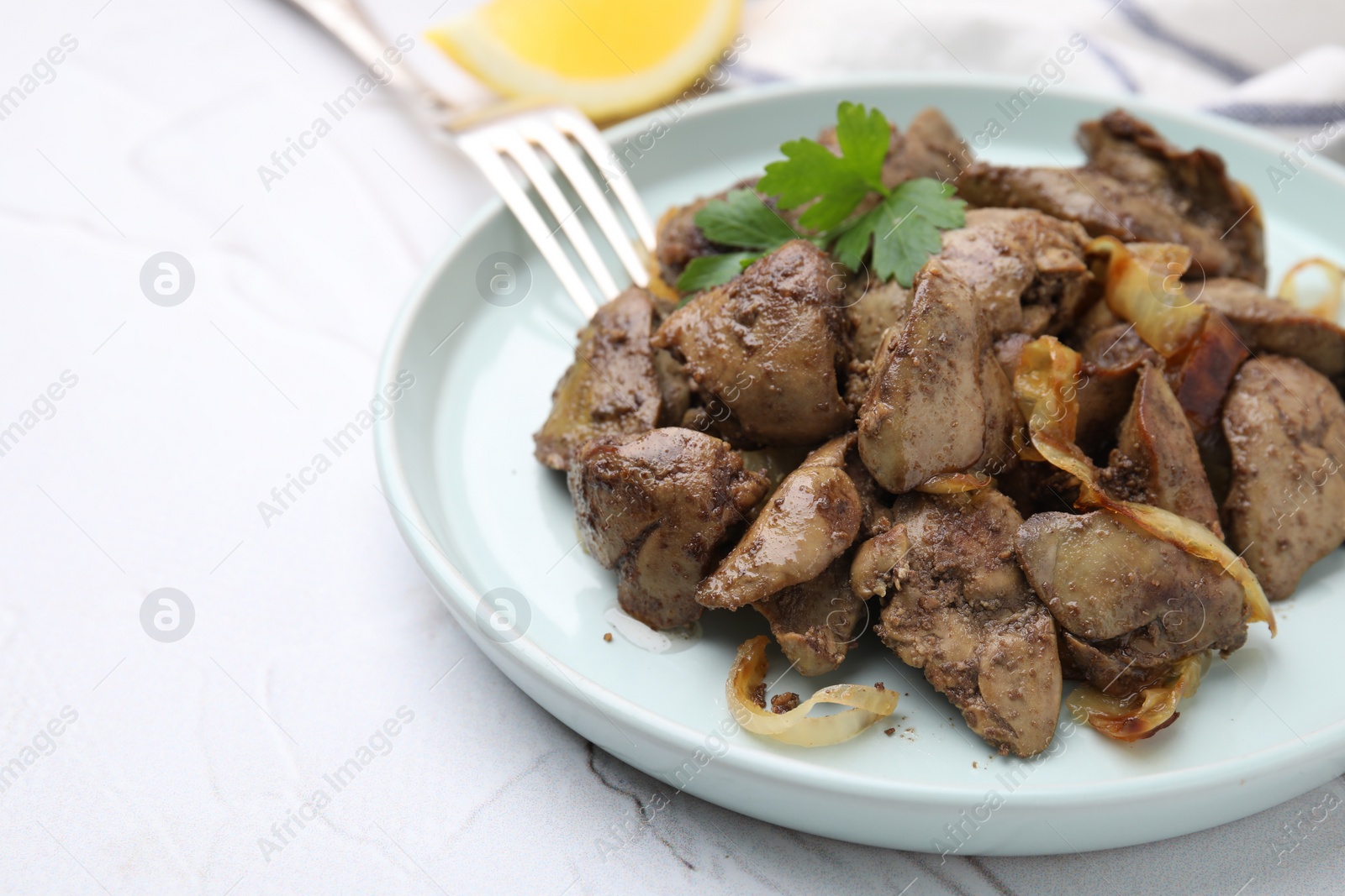 Photo of Tasty fried chicken liver with onion and fork on white textured table, space for text