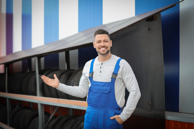 Photo of Mechanic near rack with car tires at service station