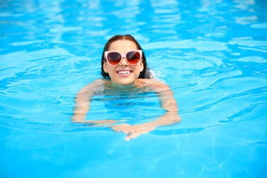 Photo of Beautiful young woman swimming in blue pool