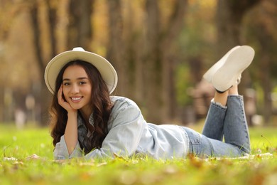 Photo of Young woman lying on green grass in park