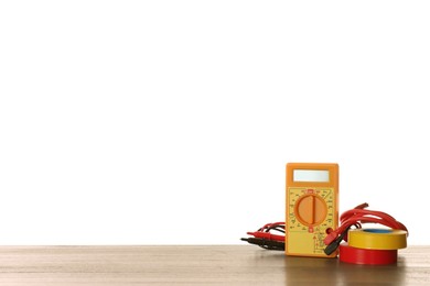 Photo of Digital multimeter and tapes on wooden table against white background. Electrician's supplies