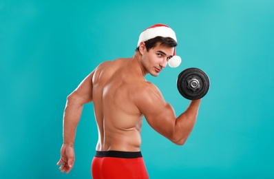 Photo of Sexy shirtless Santa Claus with dumbbell on blue background