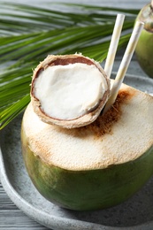 Photo of Fresh green coconut with drinking straws on table