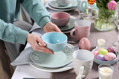 Photo of Woman setting table for festive Easter dinner at home, closeup