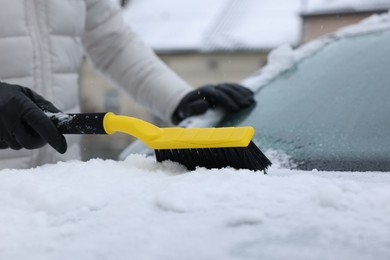 Photo of Man cleaning snow from car hood outdoors, closeup