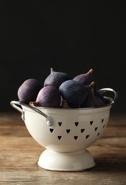 Photo of Tasty fresh figs on wooden table against black background