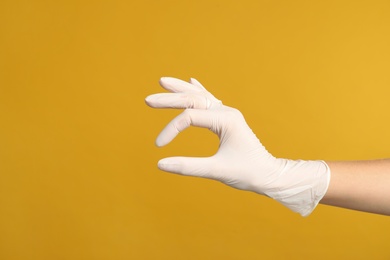 Photo of Doctor in medical gloves showing OK gesture on yellow background, closeup. Space for text