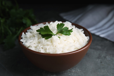 Photo of Bowl with tasty cooked rice on grey table, closeup