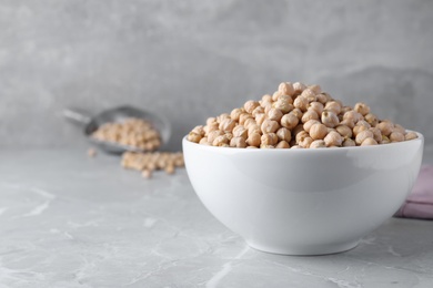 Photo of Chickpeas in bowl on light grey table, space for text