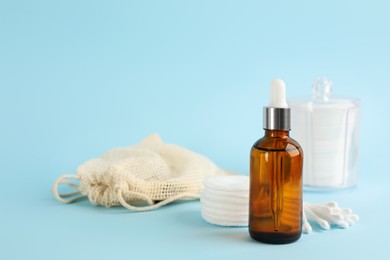 Photo of Cotton pads, swabs and makeup removal product on light blue background