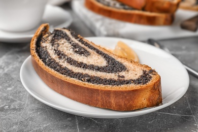 Photo of Piece of tasty sweet bun with poppy seeds on gray table