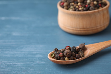 Different peppercorns  on blue wooden table, closeup. Space for text