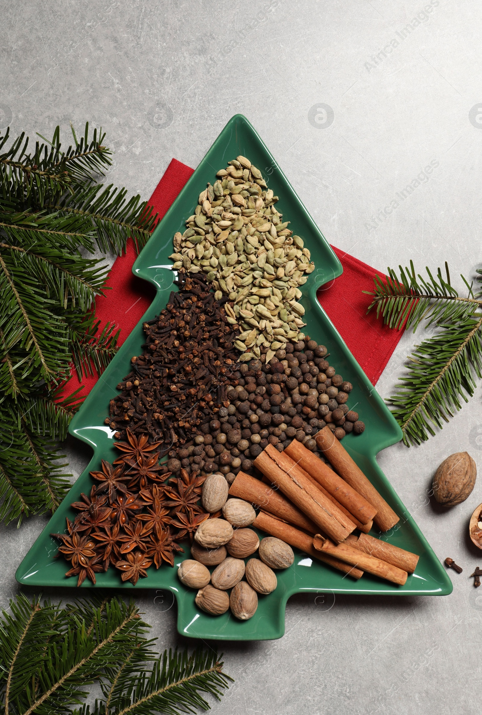 Photo of Different spices, nuts and fir branches on light gray textured table, flat lay