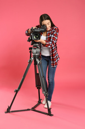 Operator with professional video camera on pink background