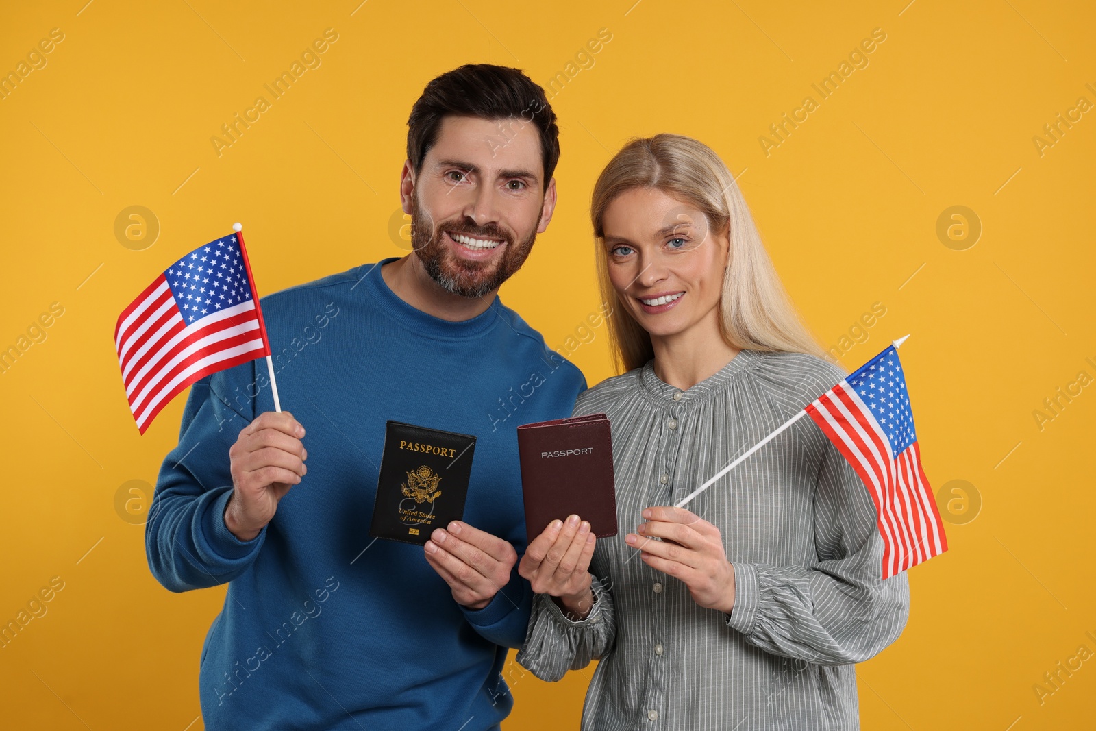 Photo of Immigration. Happy couple with passports and American flags on orange background