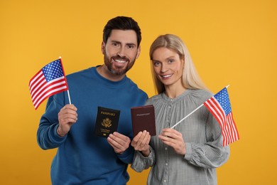Photo of Immigration. Happy couple with passports and American flags on orange background