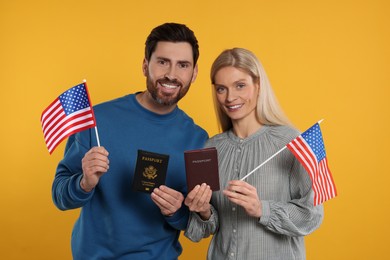 Immigration. Happy couple with passports and American flags on orange background