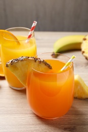 Pineapple and orange juices in glasses on wooden table, closeup