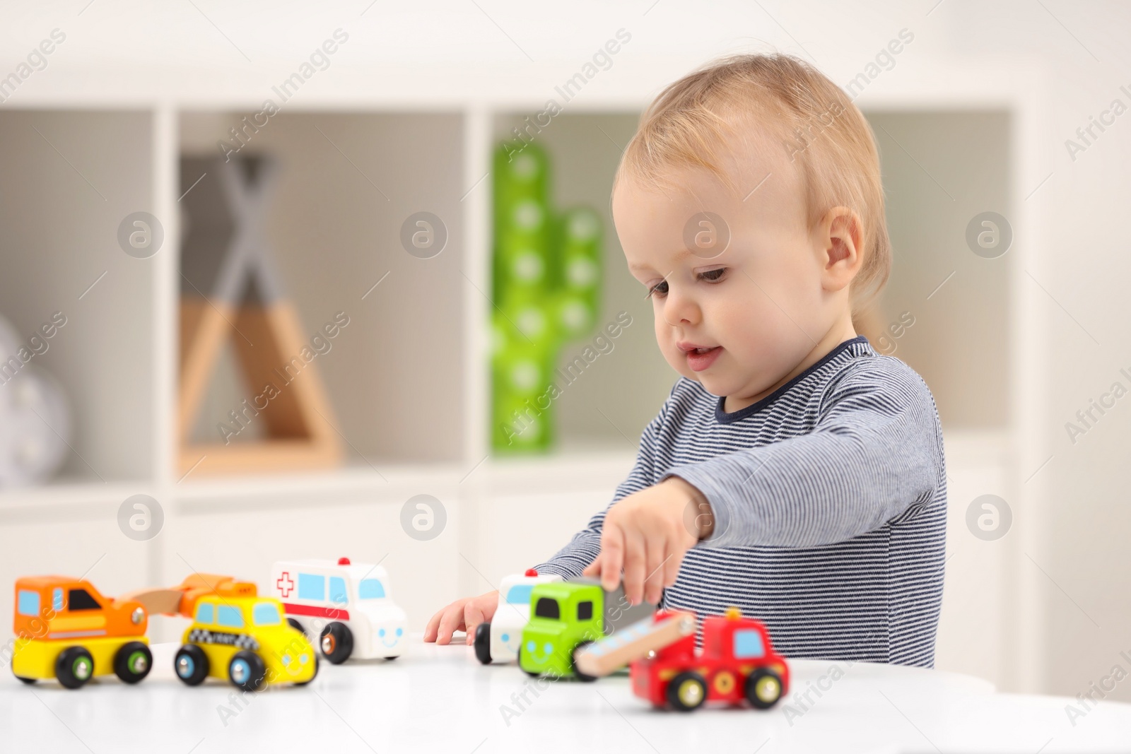 Photo of Children toys. Cute little boy playing with toy cars at white table in room, space for text