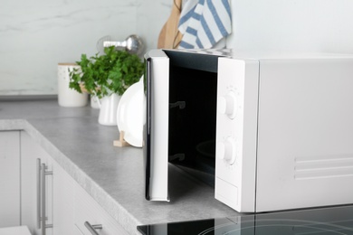 Photo of Open modern microwave oven on table in kitchen