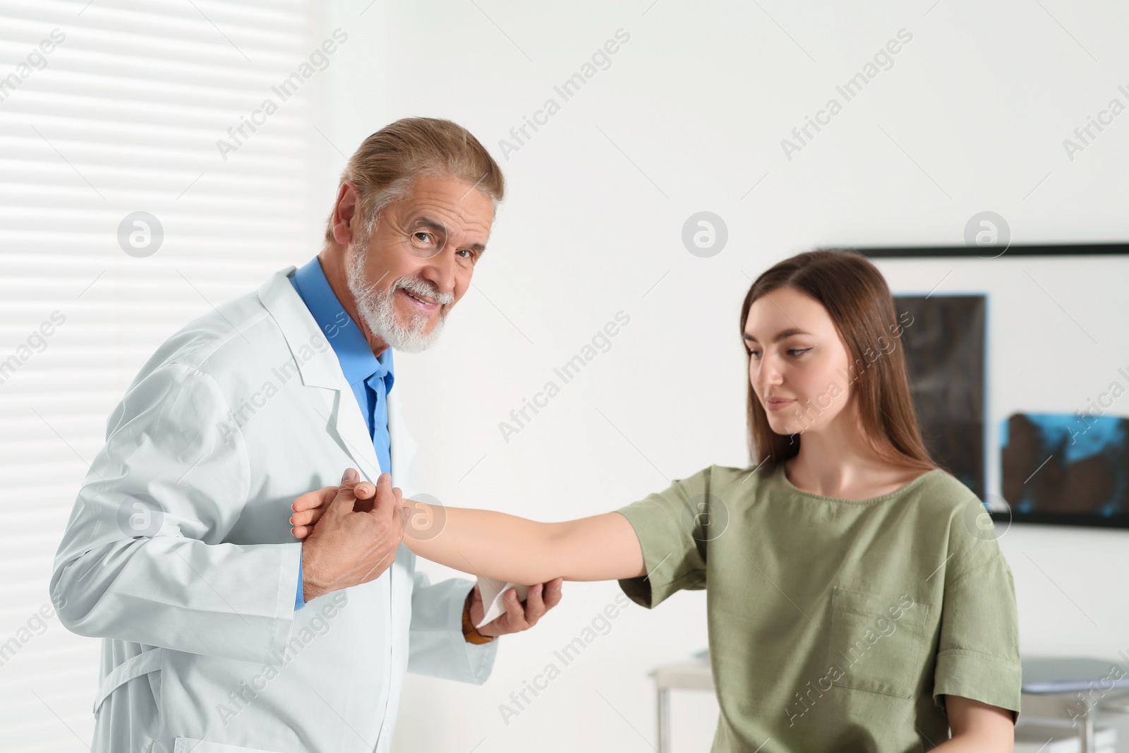 Photo of Orthopedist examining patient with injured arm in clinic