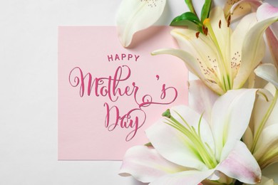 Image of Happy Mother's Day greeting card and beautiful lily flowers on white background, flat lay