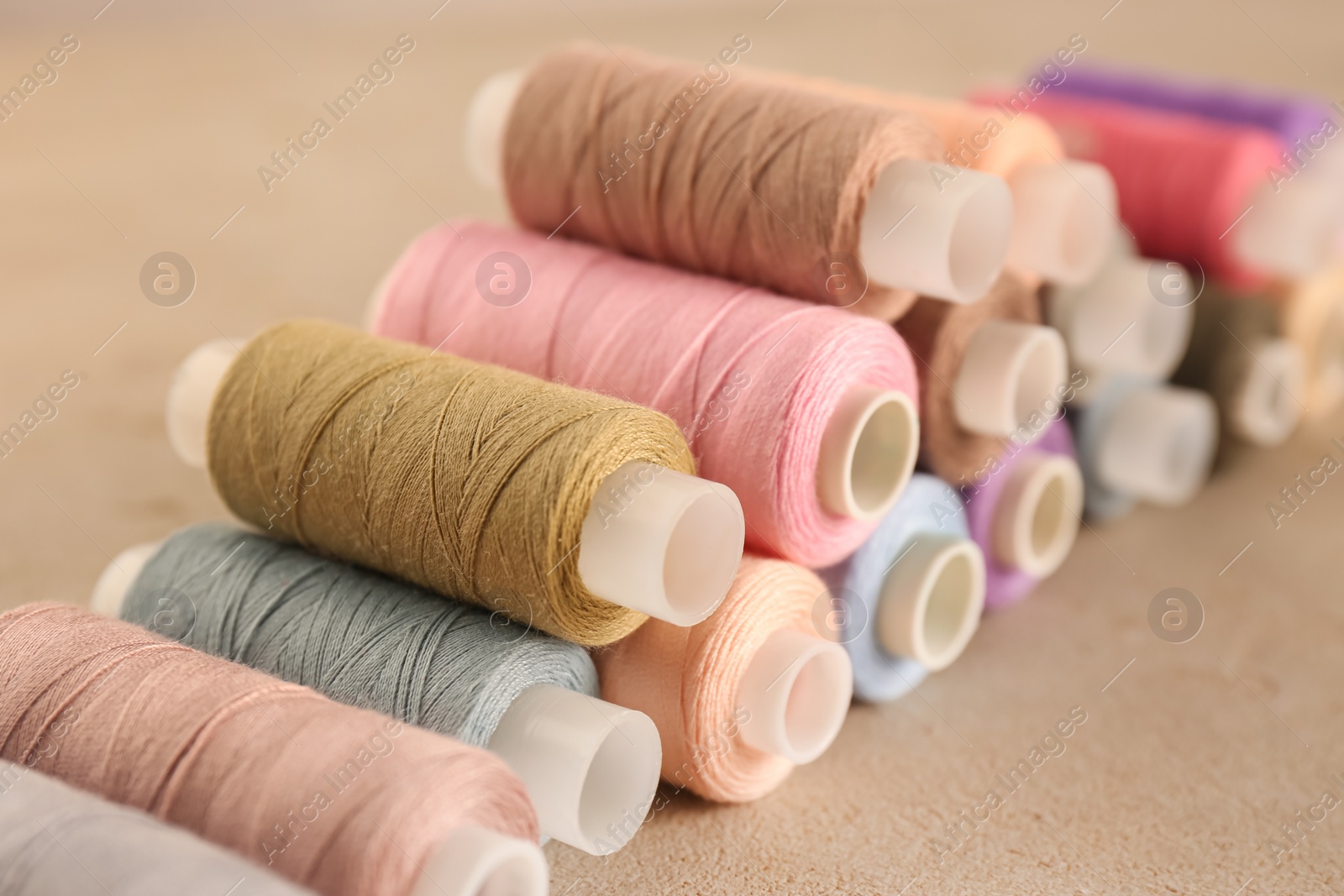 Photo of Set of color sewing threads on grey table, closeup