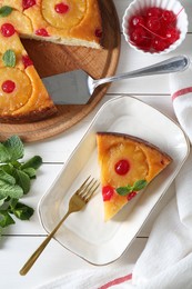 Delicious cut pineapple pie with cherry and mint on white wooden table, flat lay