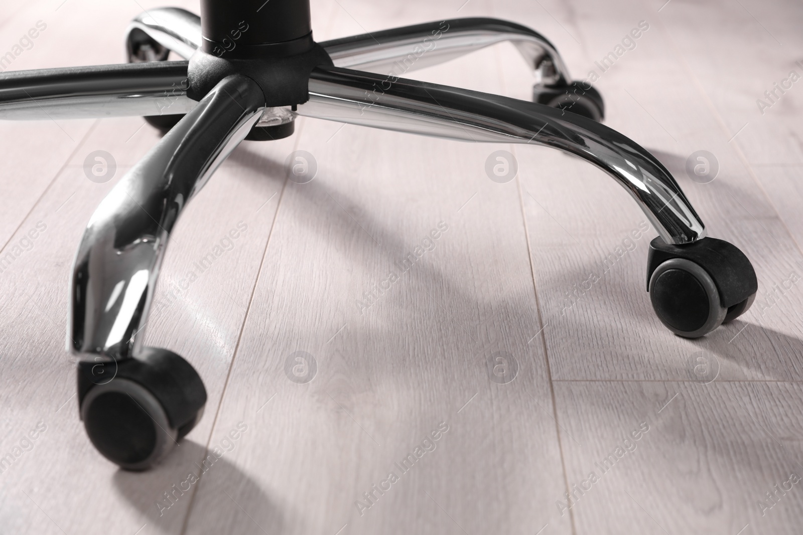 Photo of Modern office chair on wooden floor, closeup. Base with casters