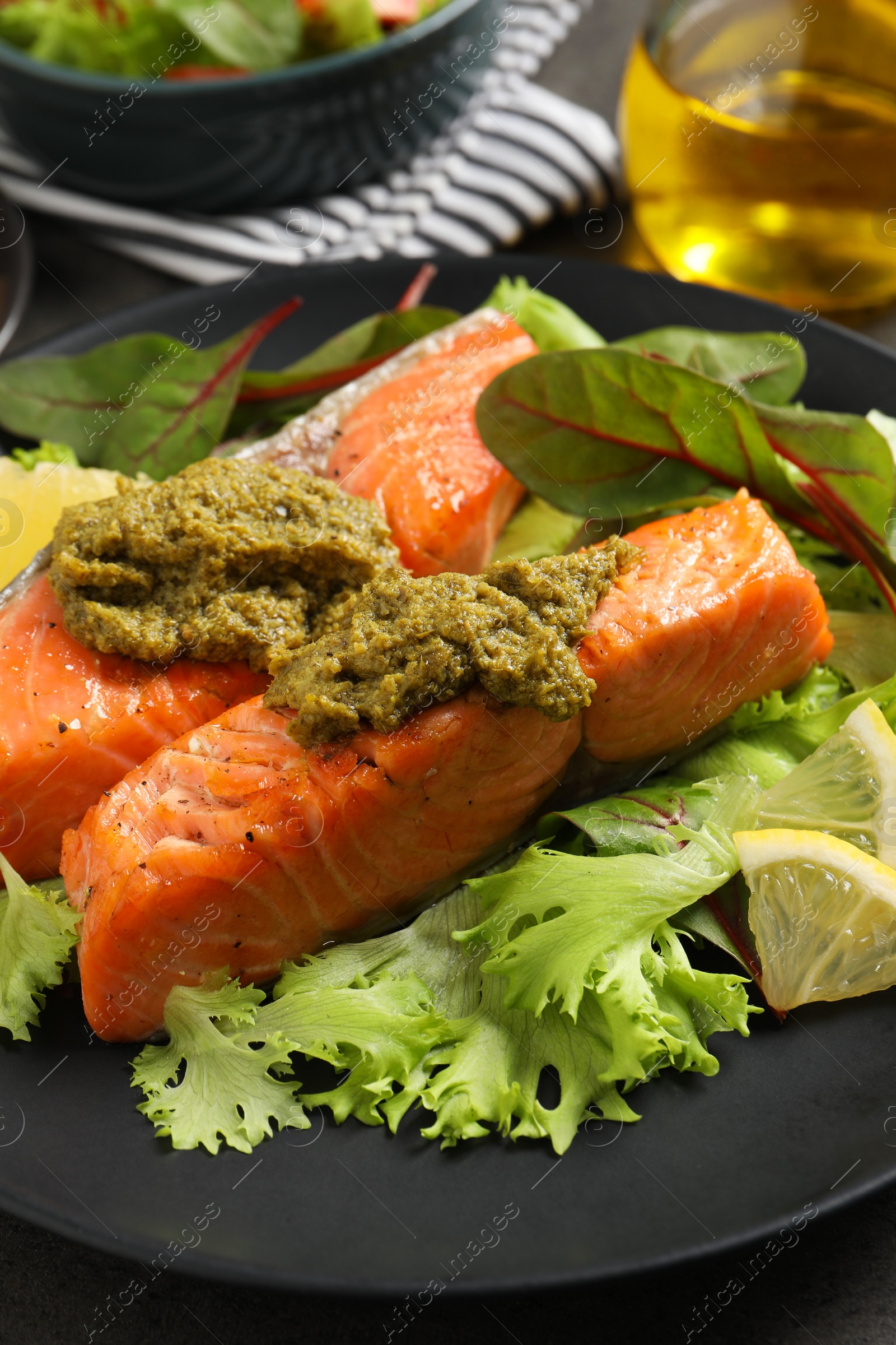 Photo of Tasty cooked salmon with pesto sauce on table, closeup