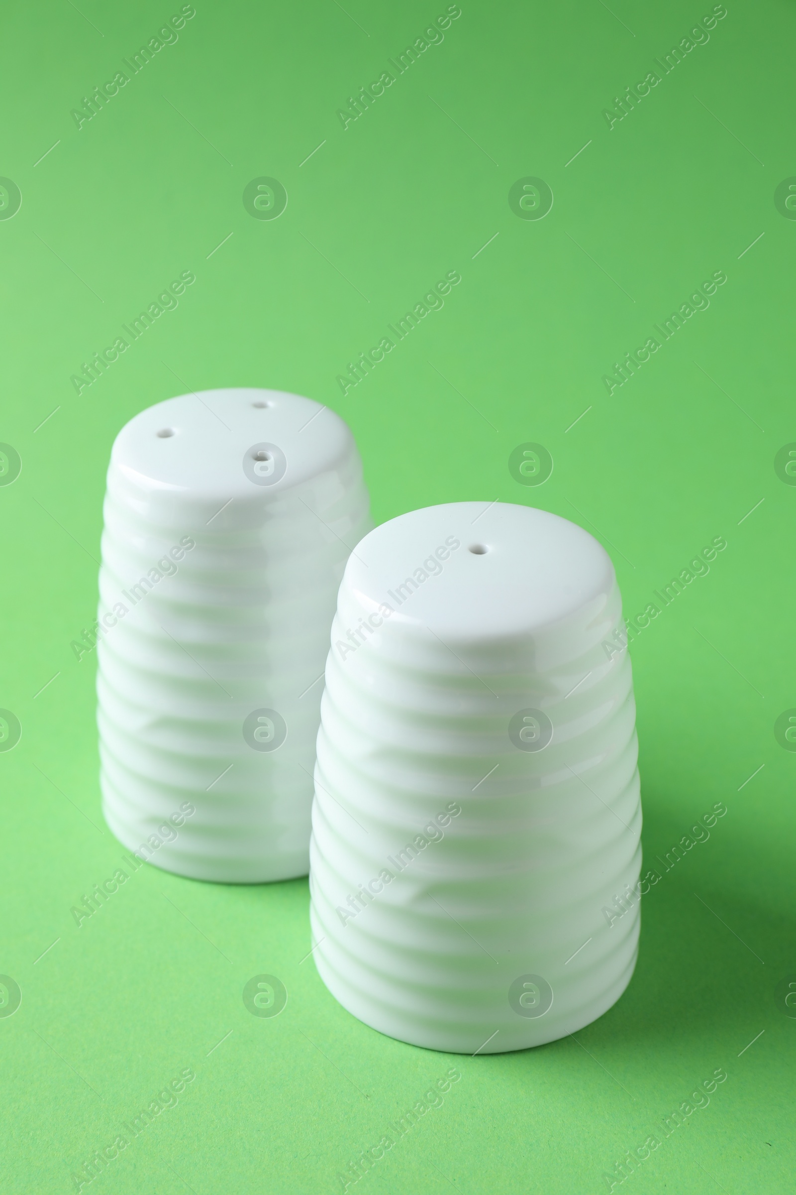 Photo of Salt and pepper shakers on green background