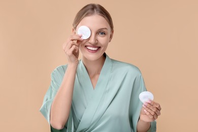 Photo of Young woman with cotton pads on beige background