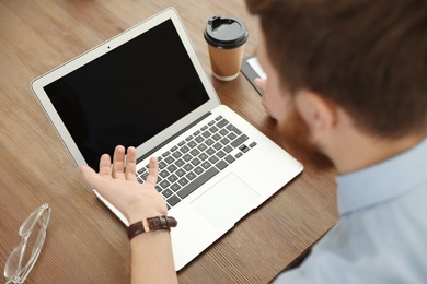 Man using video chat on laptop in home office, closeup. Space for text