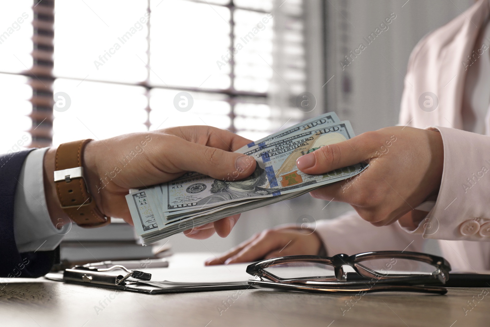 Photo of Man giving bribe to woman at table in office, closeup