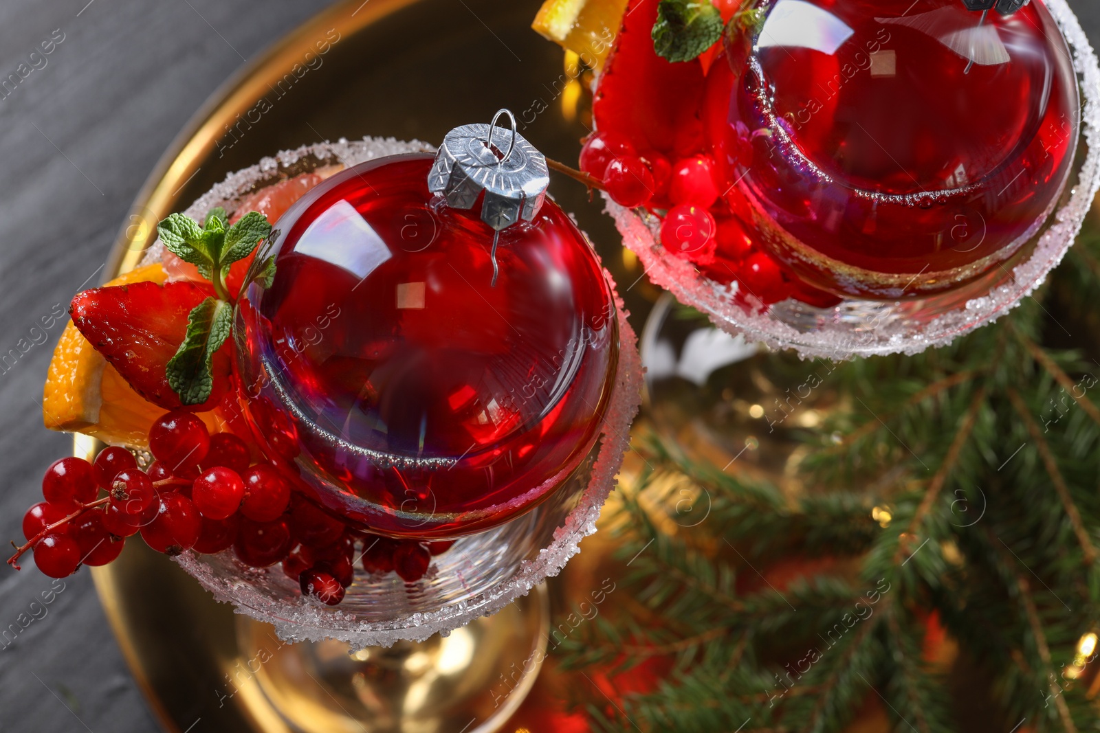 Photo of Creative presentation of Christmas Sangria cocktail in baubles and glasses on grey table, top view