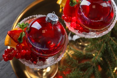 Photo of Creative presentation of Christmas Sangria cocktail in baubles and glasses on grey table, top view