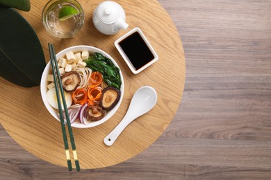 Photo of Delicious vegetarian ramen served on wooden table, flat lay with space for text. Noodle soup