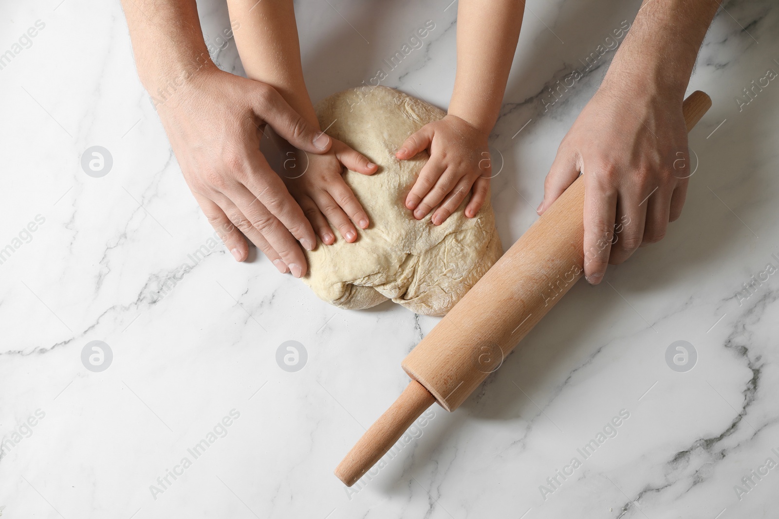 Photo of Father and child making dough at white table, top view