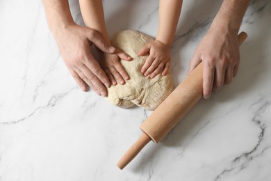 Photo of Father and child making dough at white table, top view