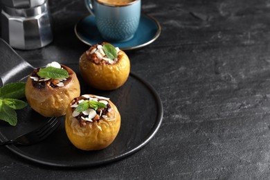 Photo of Delicious baked apples with nuts and mint served on black table, space for text