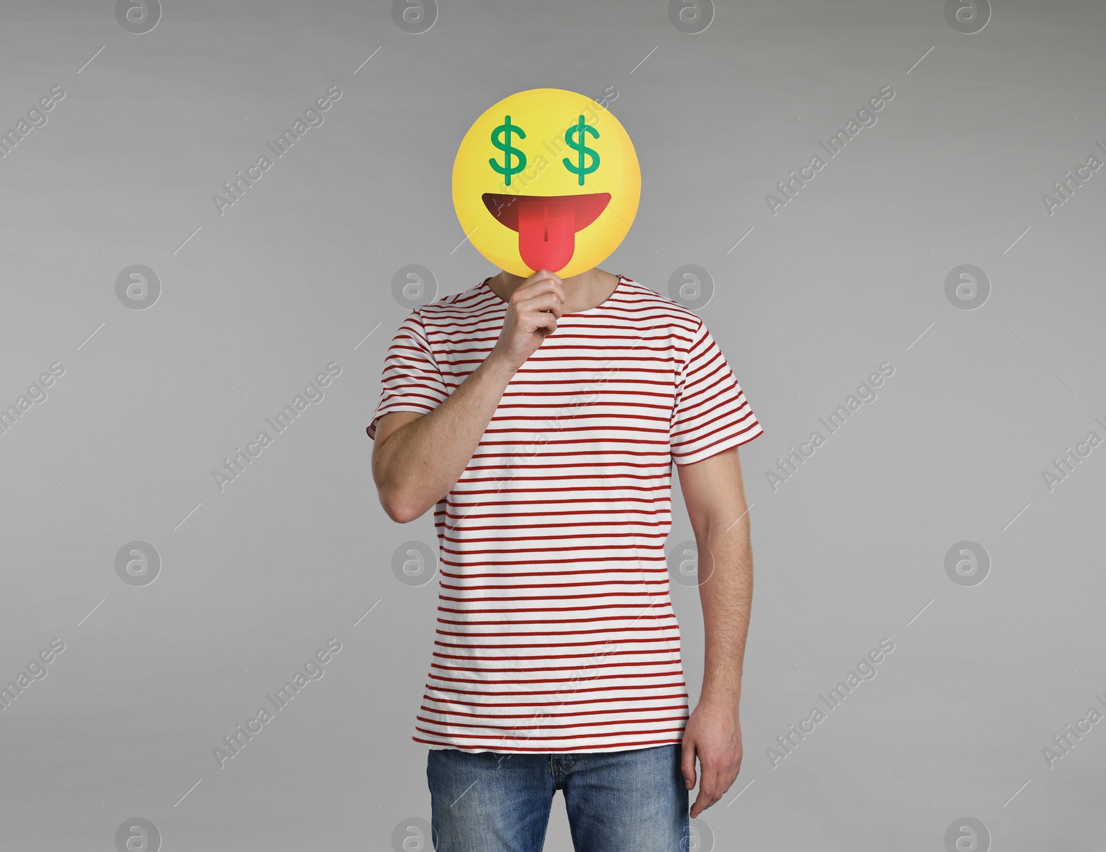Photo of Man holding emoticon with dollar signs instead of eyes on grey background