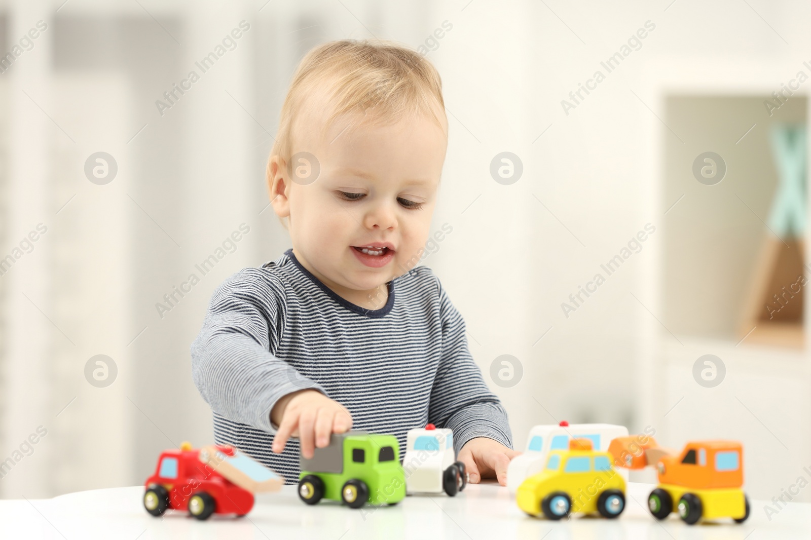 Photo of Children toys. Cute little boy playing with toy cars at white table in room