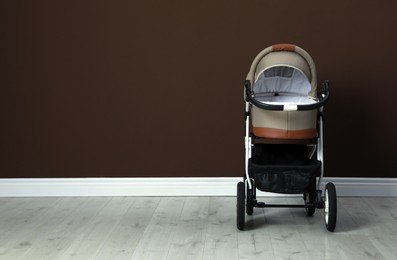 Photo of Baby carriage. Modern pram near brown wall, space for text