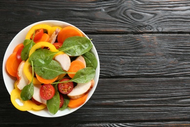 Photo of Delicious fresh chicken salad served on black wooden table, top view. Space for text