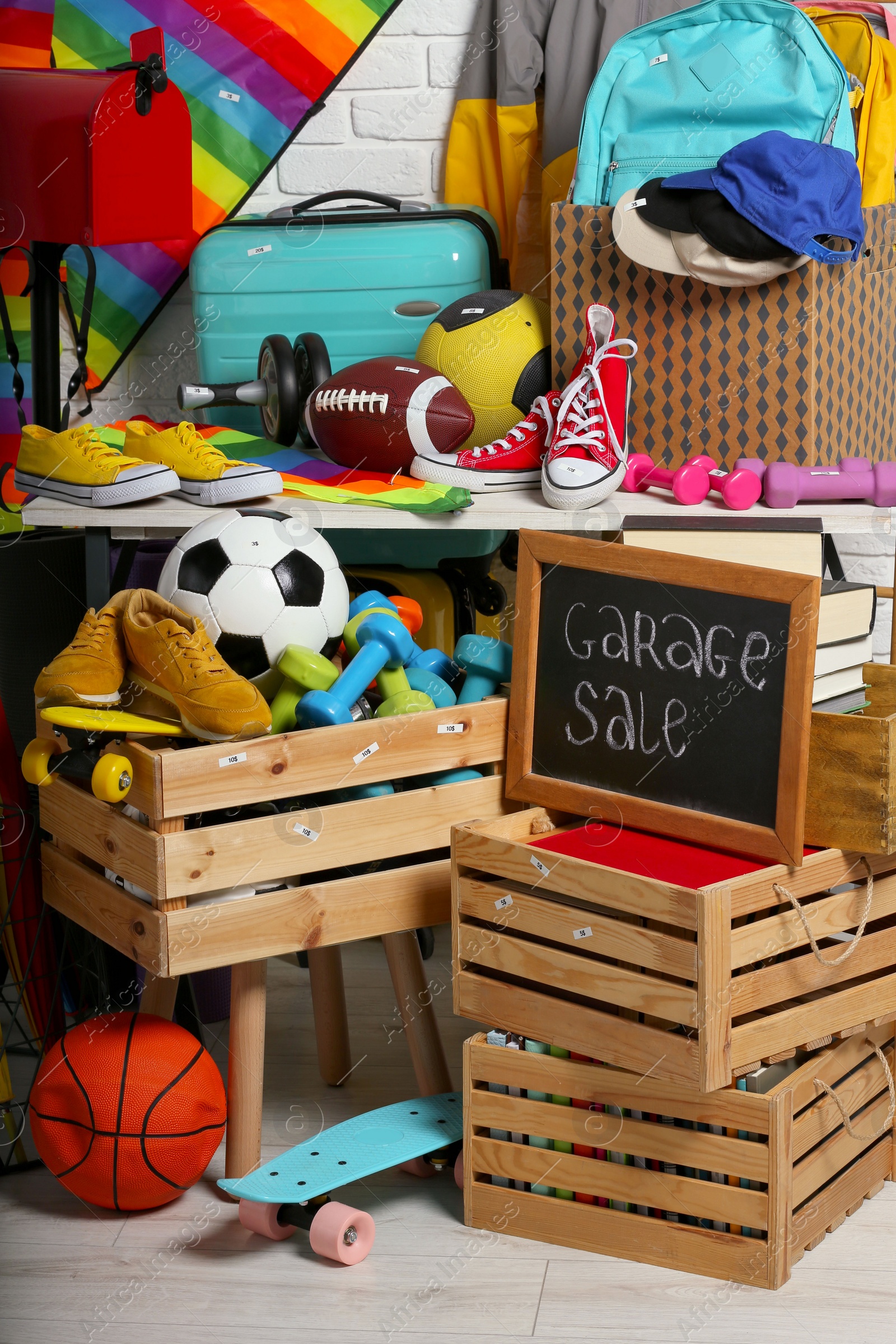 Photo of Sign Garage Sale written on blackboard near many different stuff indoors