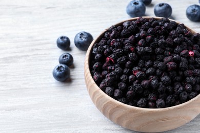 Photo of Freeze dried and fresh blueberries on white wooden table, closeup. Space for text