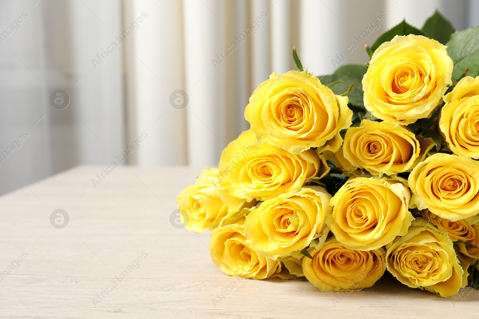 Photo of Beautiful bouquet of yellow roses on wooden table indoors, closeup. Space for text